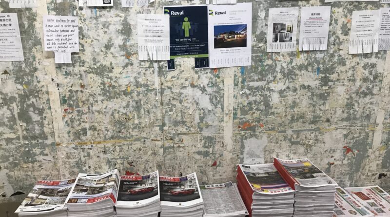 Sunnybank公告墙，上半部贴满传单，下半部空墙，墙根堆叠中文报纸