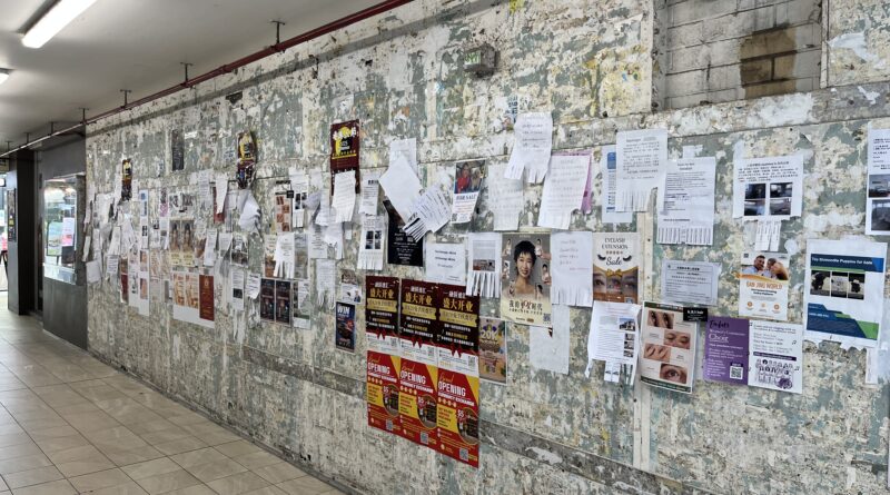 Sunnybank灰色公告墙，角度拍摄，层层叠叠的彩色海报和传单