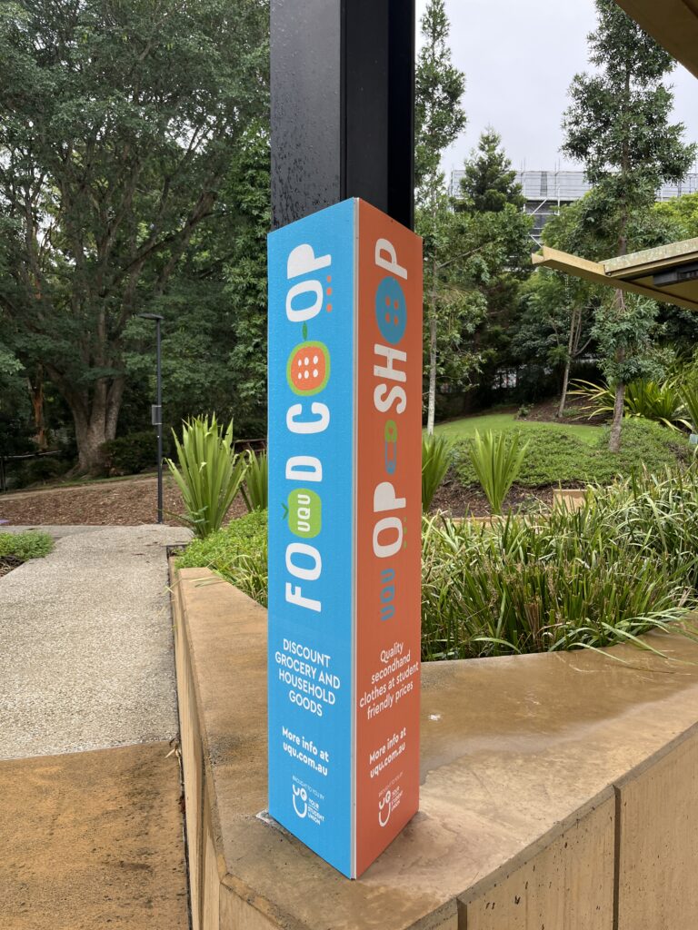 UQ湖边公交站通往校园的步道旁，学生会设立的彩色标识牌，宣传食品合作社和学生食物银行服务。