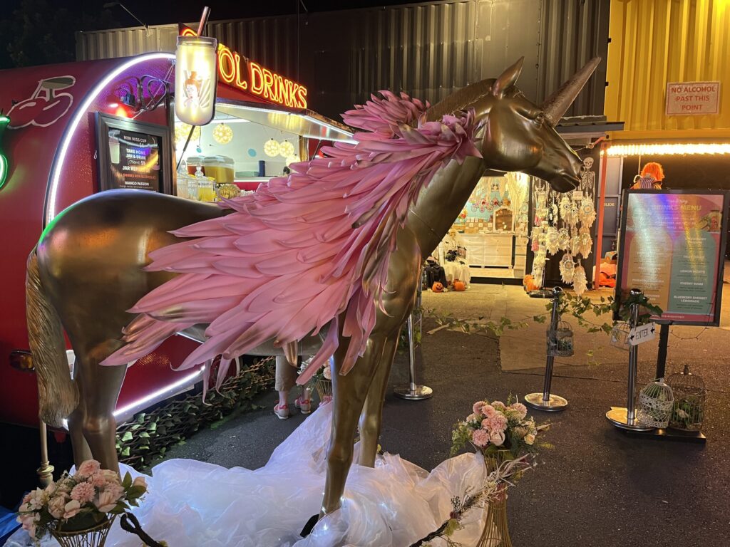 Eat Street夜市，红色冷饮拖车前，金色独角兽站在云朵上，粉色翅膀