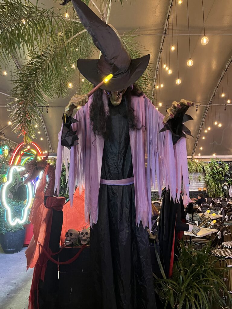 Eat Street夜市，高个女巫黑袍紫腰带，手持发光魔杖，低头俯视