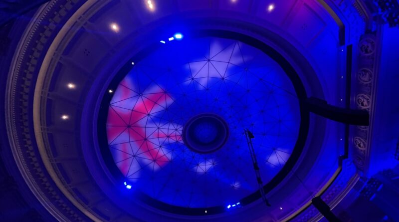 布里斯班市政厅礼堂穹顶天花板，中央玻璃采光板，环形纹路，澳洲国旗投影，蓝紫色灯光，红白蓝配色