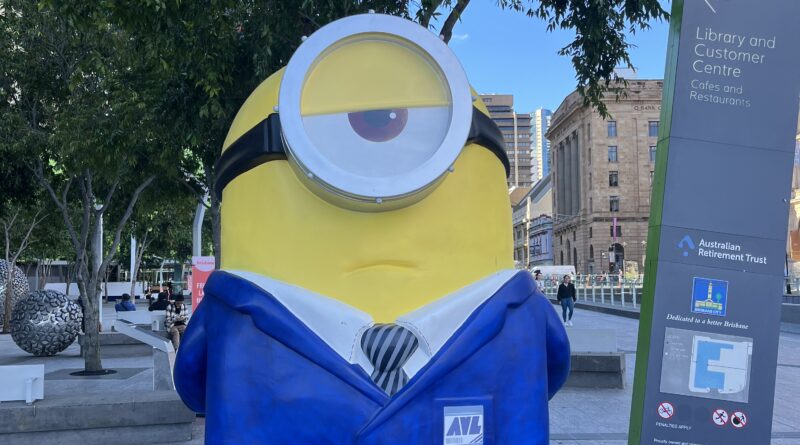 布里斯班广场，路标指向布里斯班市立图书馆，蓝色小黄人单手背后思考表情