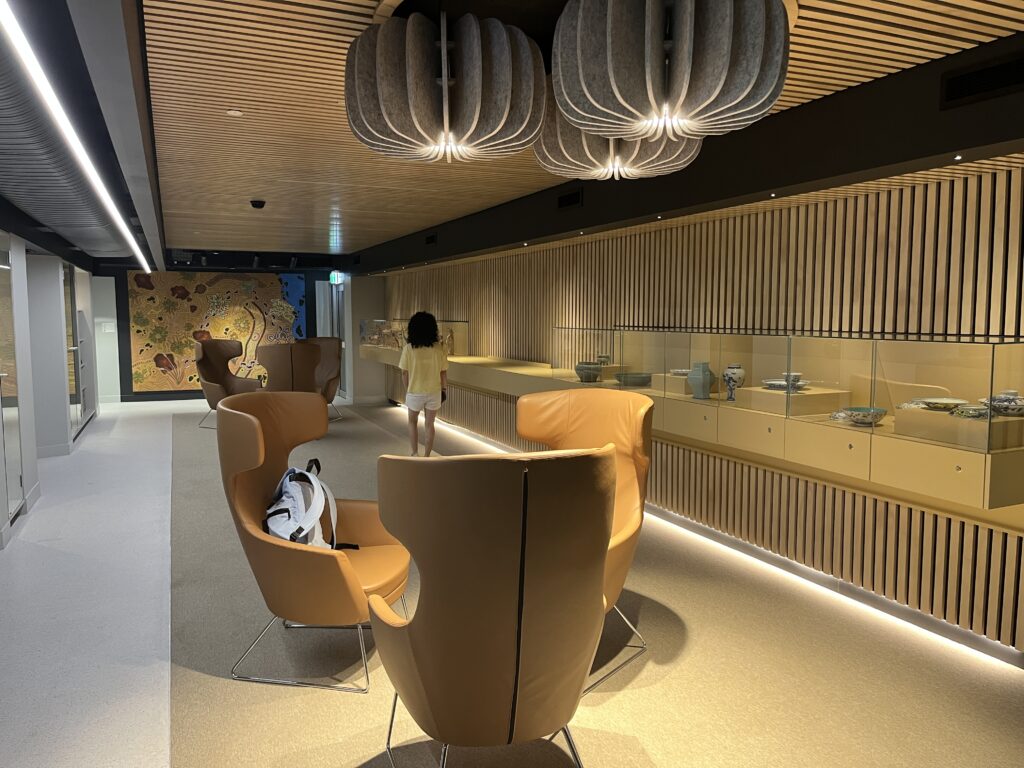 中国古玩展厅内，玻璃柜展示瓷器，皮革蛋椅供学生阅读