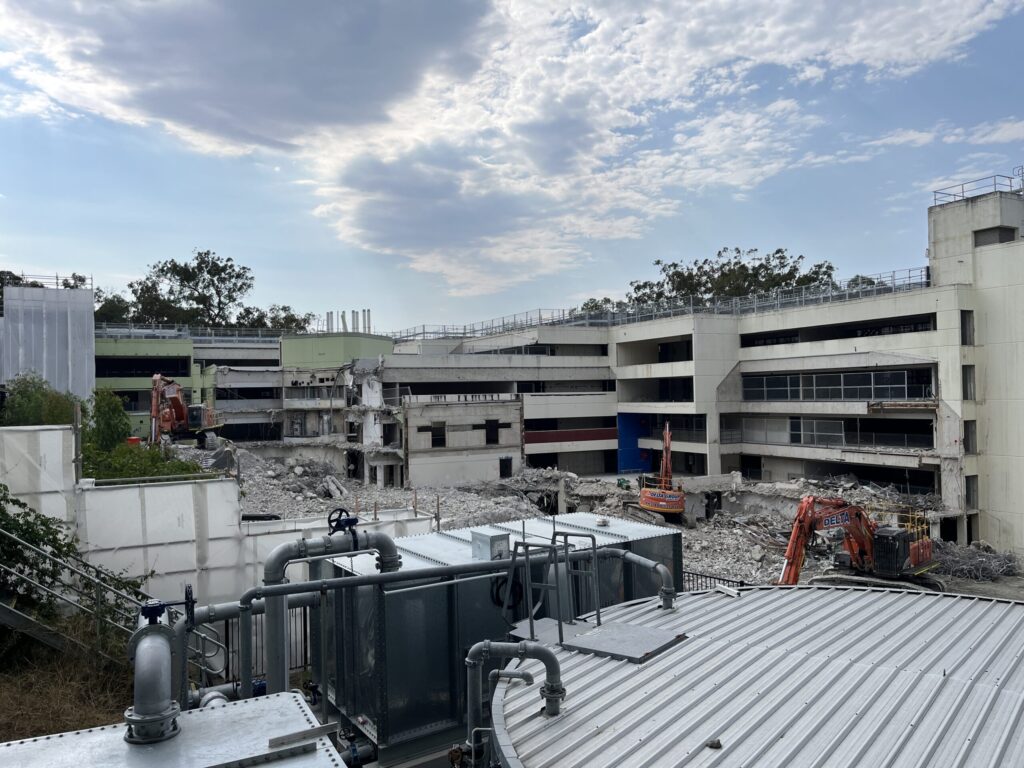 格里菲斯大学内森校区工地，三座塔吊拆除建筑，灰色混凝土楼背景，蓝天白云