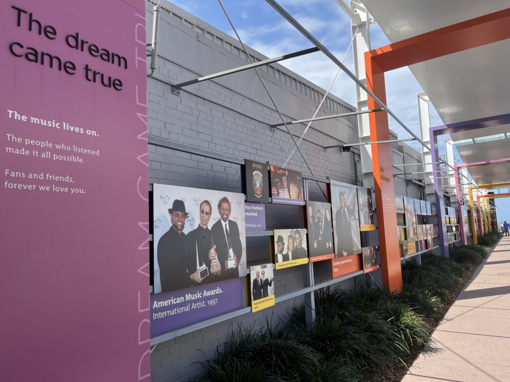 比吉斯之路粉色纪念板写着音乐永存，粉丝和朋友让梦想成真