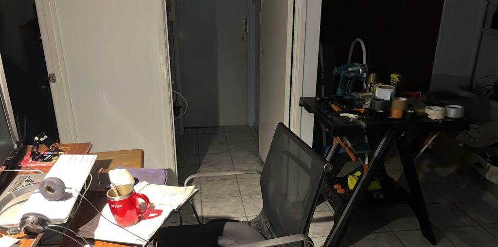 气旋第一夜深夜，走廊临时书桌，台灯亮着，远处维修工具站，远离窗户