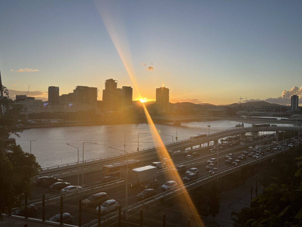 皇后码头户外用餐区俯瞰东南高速，日落时分堵车缓慢移动，两道反向光线，远处维多利亚桥