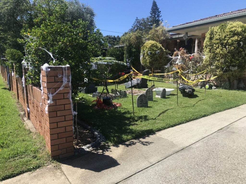 白天郊区前院万圣节装饰，灰色墓碑，女巫大锅，骷髅，死神，蜘蛛网，犯罪现场胶带