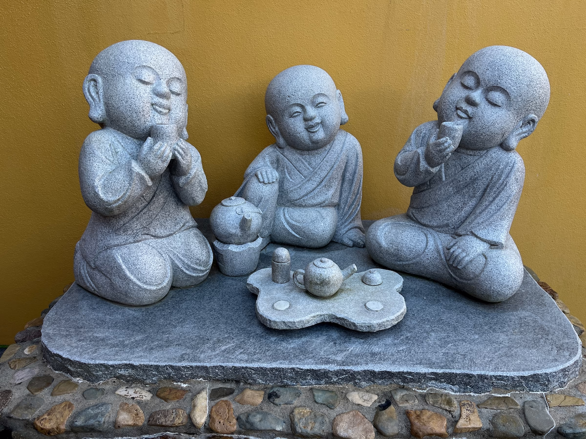 中天寺三尊石僧围坐茶桌喝茶，微笑，背景黄金色寺院墙面