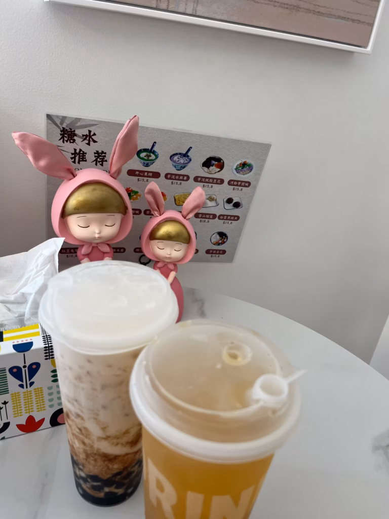 Landy's Sweet House桌面俯拍，黑糖奶茶与绿茶，穿粉兔装女仆摆件，彩色纸巾盒，墙上甜品菜单