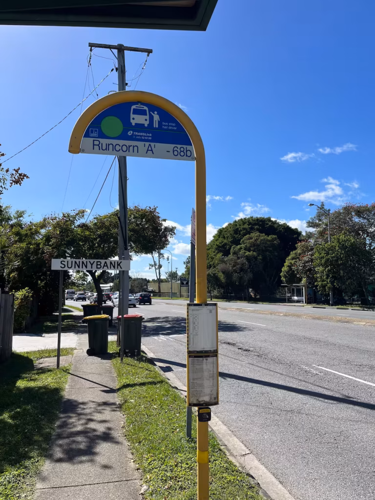 Sunnybank郊区路标，Mains Road旁人行道，木质电线杆，垃圾桶，Runcorn A公交站，蓝天阳光