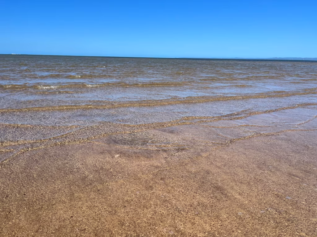 威灵顿角沙洲浅浪，清澈见底，沙面可见，上方地平线与蓝天