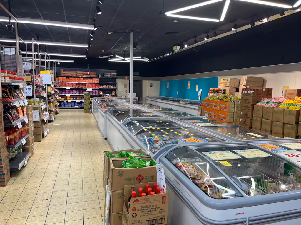 亚洲超市冷冻食品区，玻璃冷柜内整齐排列冷冻饺子、点心、肉类、海鲜