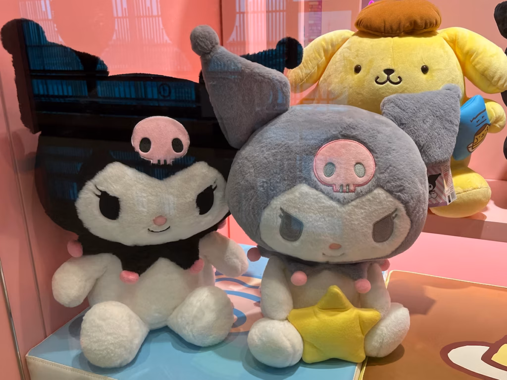 台北机场Hello Kitty商店橱窗，黑色与灰色Kuromi布偶，灰色手持黄色星星，后方Pompompurin布偶观望