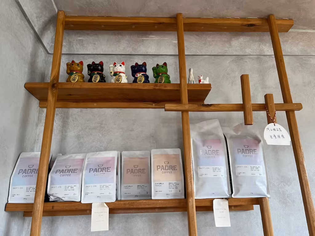 Runcorn 咖啡馆内，深色木架上招财猫摆件，周围本地手作陶瓷工艺品，温馨小店氛围