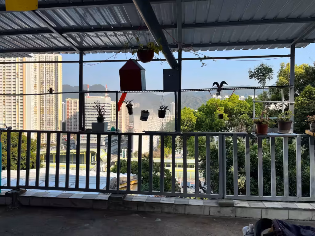 香港山坡村屋外望，俯瞰城市住宅区与远山，密集楼宇与绿色山丘