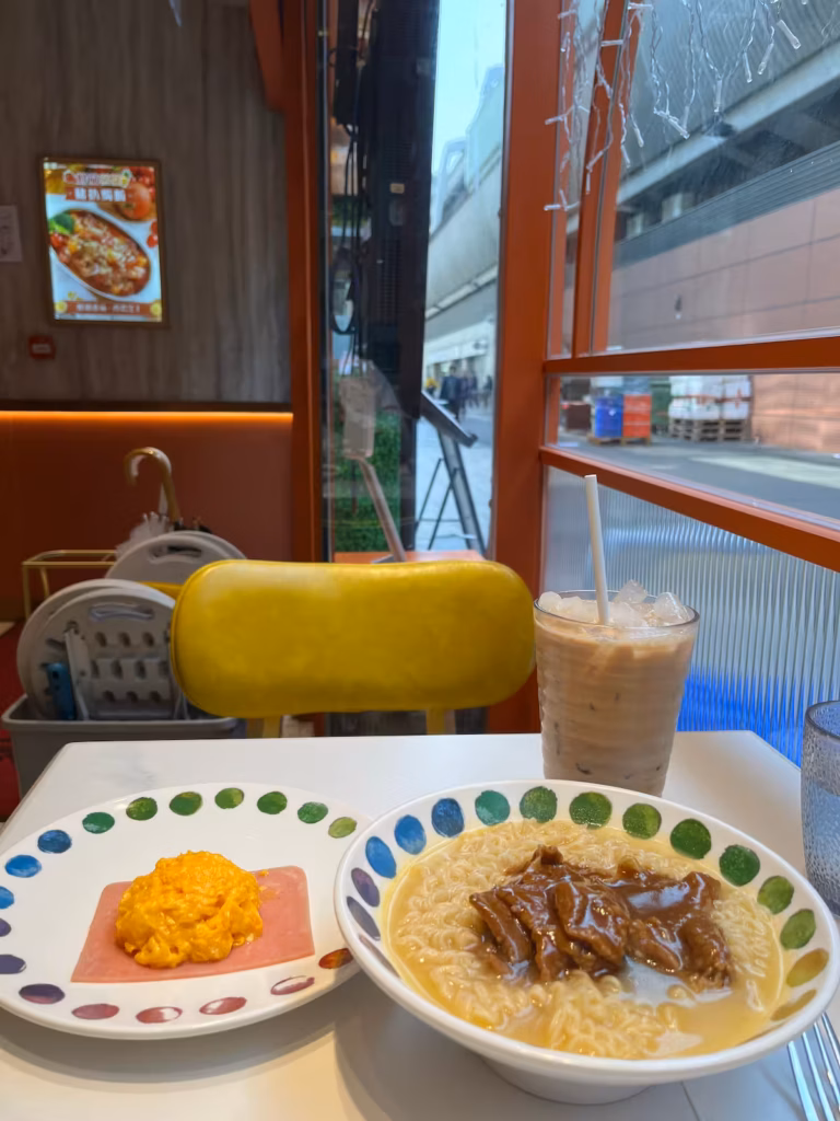 香港茶餐厅早餐，沙爹牛肉方便面，火腿煎蛋卷，冰奶茶，黄色空椅，桌面俯视